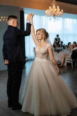 Gelin ve damadın ilk düğün dansı gün batımında restoranın içinde.