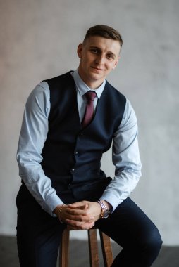 Stüdyoda mavi takım elbiseli neşeli bir damadın portresi.