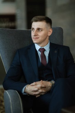 Stüdyoda mavi takım elbiseli neşeli bir damadın portresi.