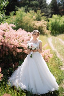 Bahar ormanında, düğün gününde beyaz elbiseli genç bir kız.