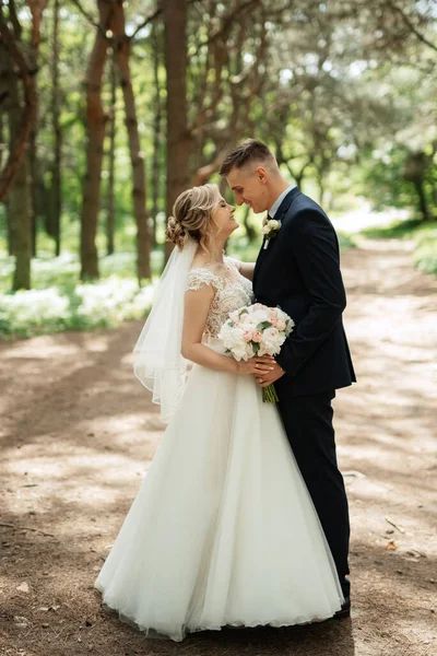 the groom and the bride are walking in the forest on a bright day