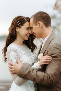 Gelin ve damadın ilk düğün dansı nehir kıyısındaki iskelede, düğün kemerinin arka planında.