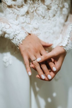 Gelin onu nazikçe tutar ve alyansa dokunur.