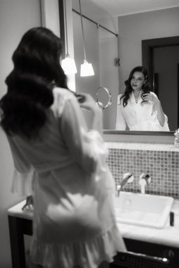 Kahverengi saçlı kız sabah banyoda aynanın önünde.