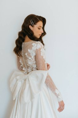 Kahverengi saçlı kız sabahları bir otel odasında gelinlik giyer.