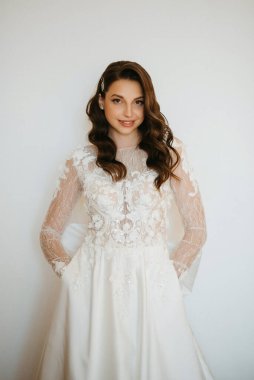 Kahverengi saçlı kız sabahları bir otel odasında gelinlik giyer.