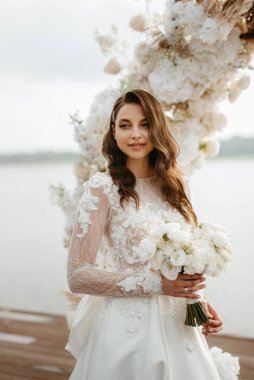 bride against the background of a yellow sunset on a pier near the river