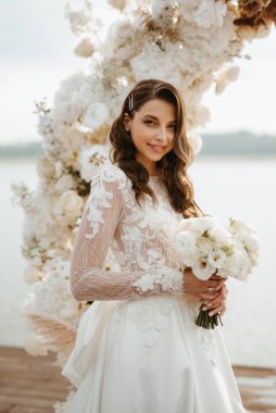 Gelin, sarı bir günbatımının arka planında nehir kıyısındaki bir iskelede