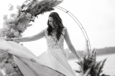 Gelin, sarı bir günbatımının arka planında nehir kıyısındaki bir iskelede