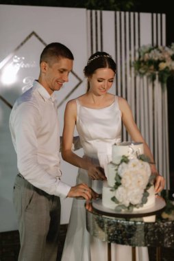 newlyweds happily cut, laugh and taste the wedding cake