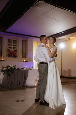 Gelin ve damadın ilk düğün dansı gün batımında restoranın içinde.