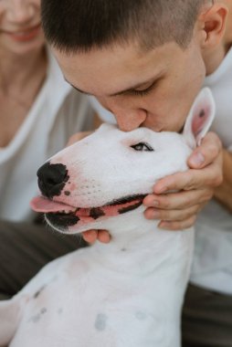 Genç bir çift, parlak bir odada köpekle oynuyorlar.