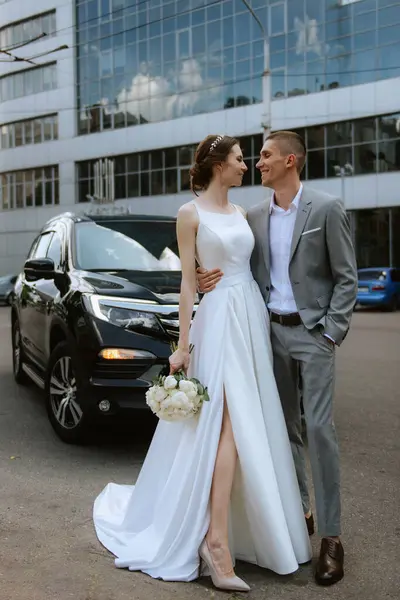 ガラスの高層ビルの近くに黒い車と花嫁とグルーミング ストック写真
