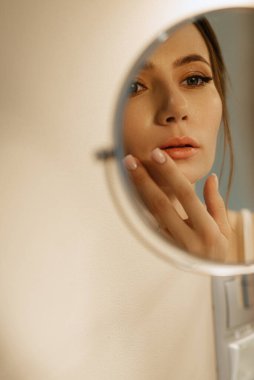bride in a veil with makeup paints her lips in the bathroom