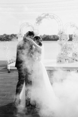 the first dance of the bride and groom inside a restaurant with heavy smoke