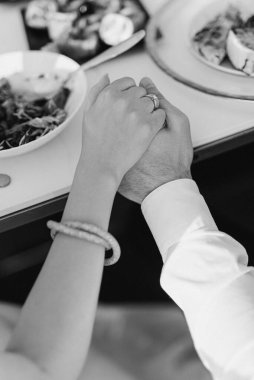 Gelin ve damat nazikçe el ele tutuşuyorlar.