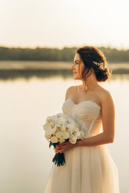 bride against the background of a yellow sunset on a pier near the river