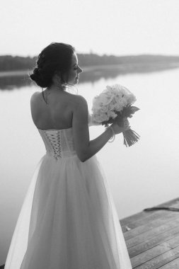 bride against the background of a yellow sunset on a pier near the river