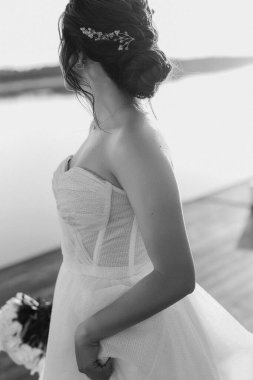 Gelin, sarı bir günbatımının arka planında nehir kıyısındaki bir iskelede