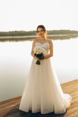 bride against the background of a yellow sunset on a pier near the river