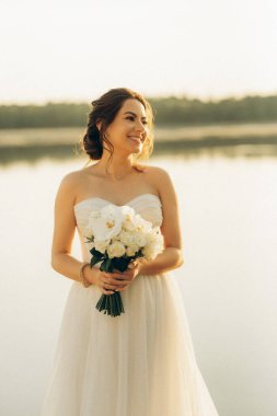 bride against the background of a yellow sunset on a pier near the river