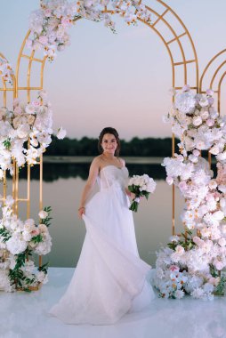 Gelin, sarı bir günbatımının arka planında nehir kıyısındaki bir iskelede