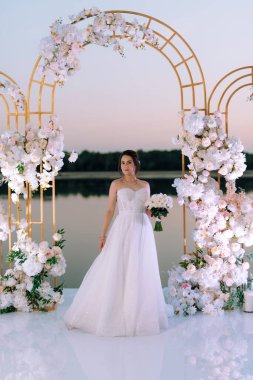 Gelin, sarı bir günbatımının arka planında nehir kıyısındaki bir iskelede