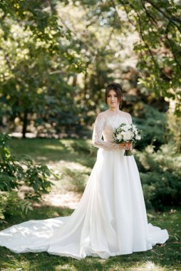 Bahar bahçesinde gelinlik giymiş genç bir kız.