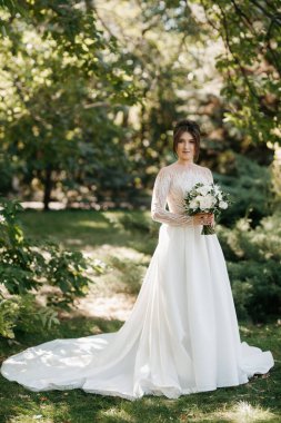 Bahar bahçesinde gelinlik giymiş genç bir kız.