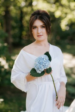 Bahar bahçesinde gelinlik giymiş genç bir kız.