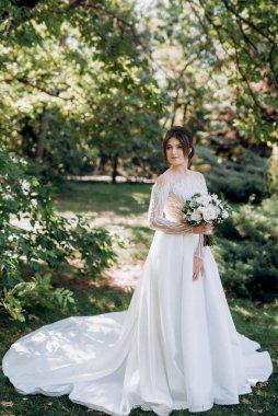 Bahar bahçesinde gelinlik giymiş genç bir kız.