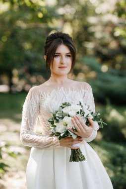 Bahar bahçesinde gelinlik giymiş genç bir kız.