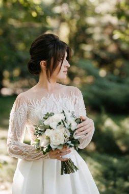 Bahar bahçesinde gelinlik giymiş genç bir kız.