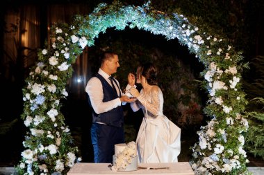newlyweds happily cut, laugh and taste the wedding cake