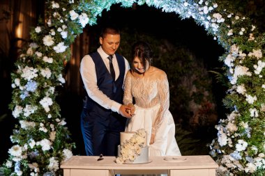 newlyweds happily cut, laugh and taste the wedding cake