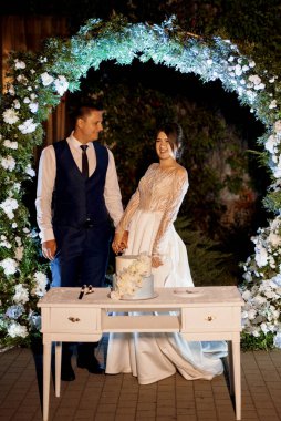 newlyweds happily cut, laugh and taste the wedding cake