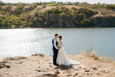 bride blonde girl and groom near the river at sunset light