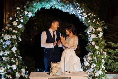 newlyweds happily cut, laugh and taste the wedding cake