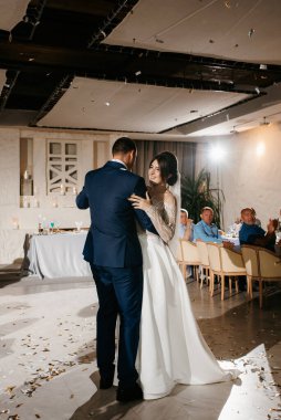 Gelin ve damadın ilk düğün dansı gün batımında restoranın içinde.