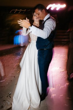 the first wedding dance of the bride and groom inside the restaurant hall in sunset light