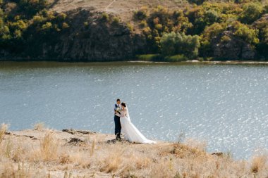 bride blonde girl and groom near the river at sunset light