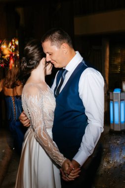 Gelin ve damadın ilk düğün dansı gün batımında restoranın içinde.