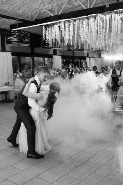 the first dance of the bride and groom inside a restaurant with heavy smoke