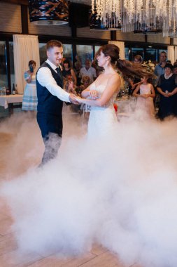 the first dance of the bride and groom inside a restaurant with heavy smoke