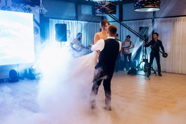 the first dance of the bride and groom inside a restaurant with heavy smoke