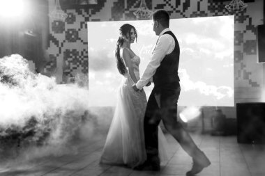 the first dance of the bride and groom inside a restaurant with heavy smoke
