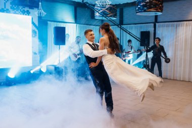 the first dance of the bride and groom inside a restaurant with heavy smoke