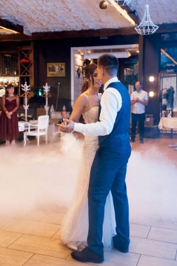 the first dance of the bride and groom inside a restaurant with heavy smoke