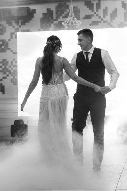 the first dance of the bride and groom inside a restaurant with heavy smoke