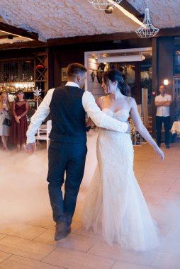 the first dance of the bride and groom inside a restaurant with heavy smoke